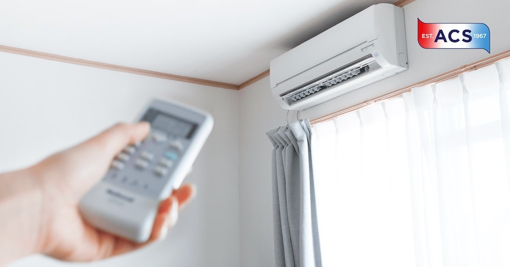 Person changing temperature on a mini-split heat pump from ACS HVAC services