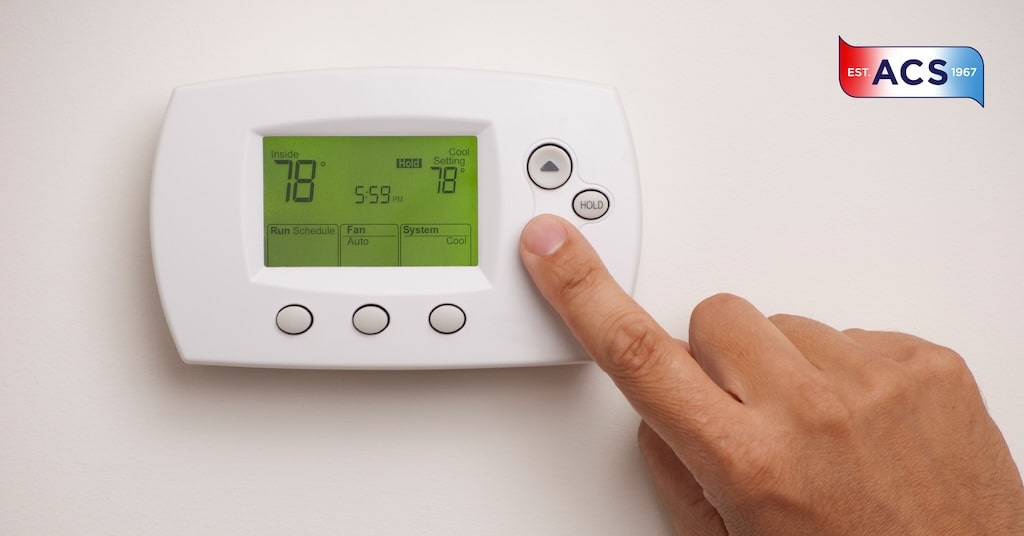 A person setting thermostat in a home