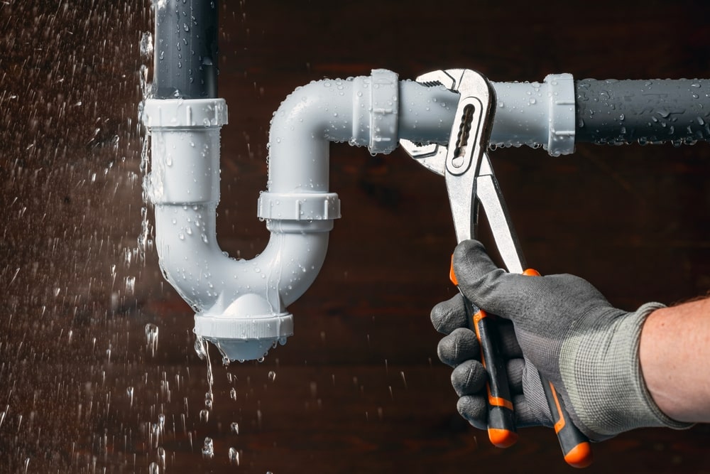 Person Trying To fix pipe with a wrench