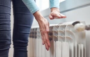 A person in Conyers warms their hands above a white radiator indoors by a window, dressed in a light blue sweater and jeans. what is heating ventilation and air conditioning